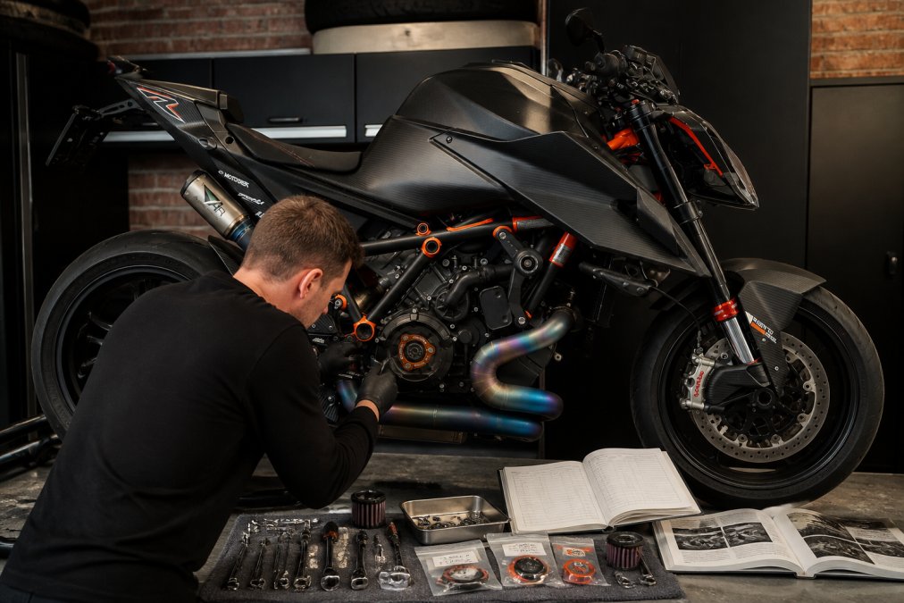 Technicus voert nauwkeurig onderhoud uit aan een performance motorfiets in een professionele werkplaats, met gereedschap, onderdelen en onderhoudsschema's zichtbaar, wat vakmanschap en zorg uitstraalt