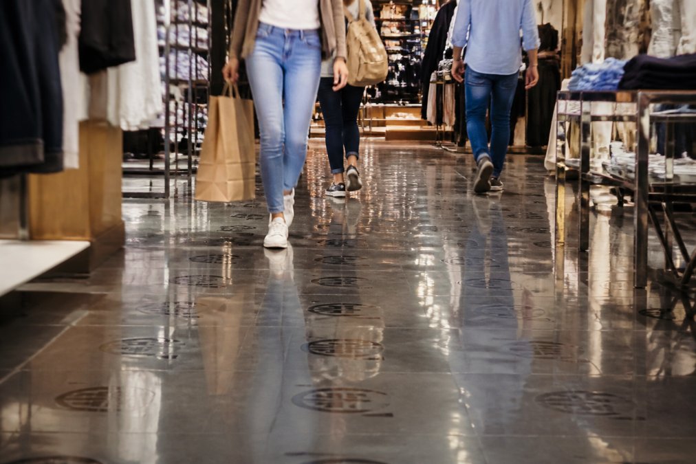 Bjarmodan alternativer til butiksgulve 2 Moderne butik med blanke PVC-fliser under høj trafik - kunder går på gulvet, og butikkens logo ses gentaget i mønsteret på den reflekterende overflade