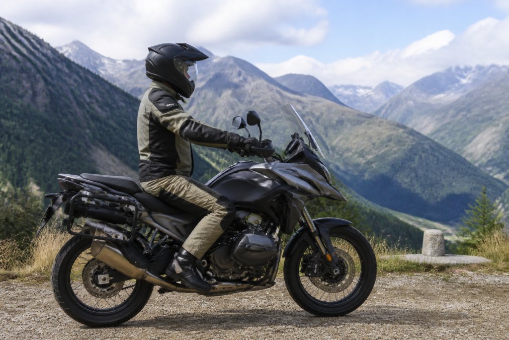 Rijder op de BMW R 1300 GS in bergachtig landschap, zittend op het zadel met duidelijk zicht op de ergonomische zitpositie, het dashboard en de handgreepplaatsing