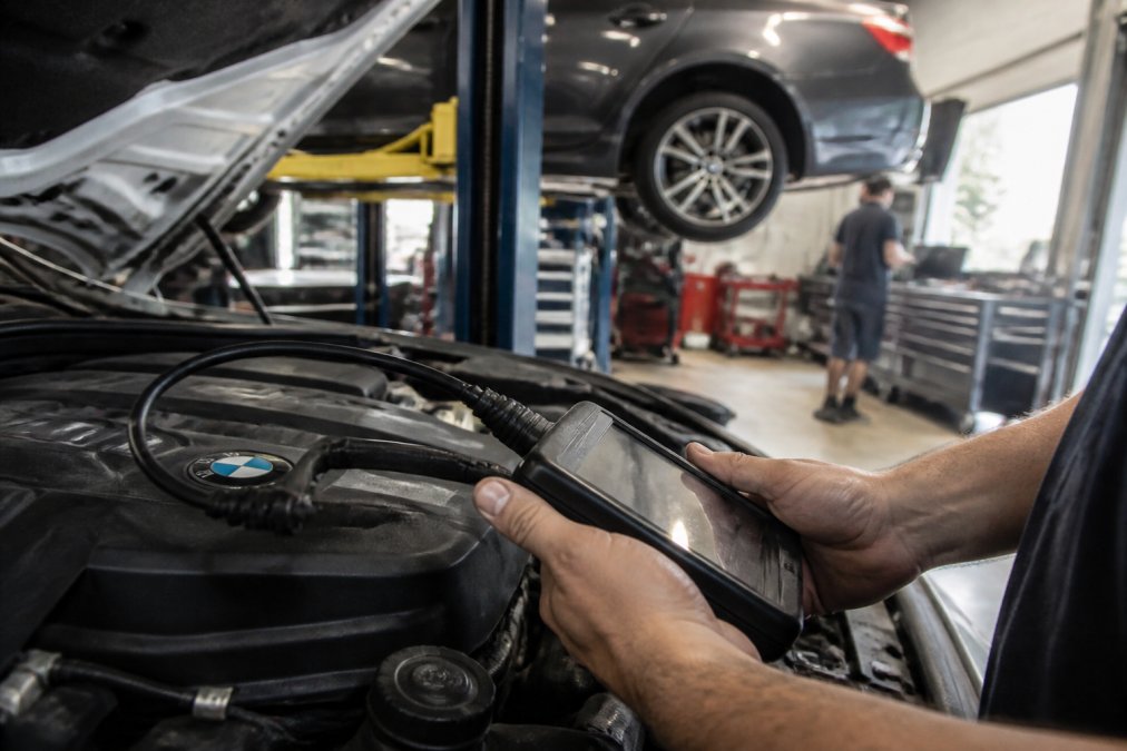 Mechanic using a diagnostic scan tool on a BMW engine during a professional BMW service appointment