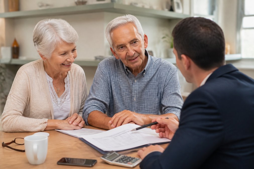 A couple reviewing financial documents with an advisor during a retirement income consultation in a bright office