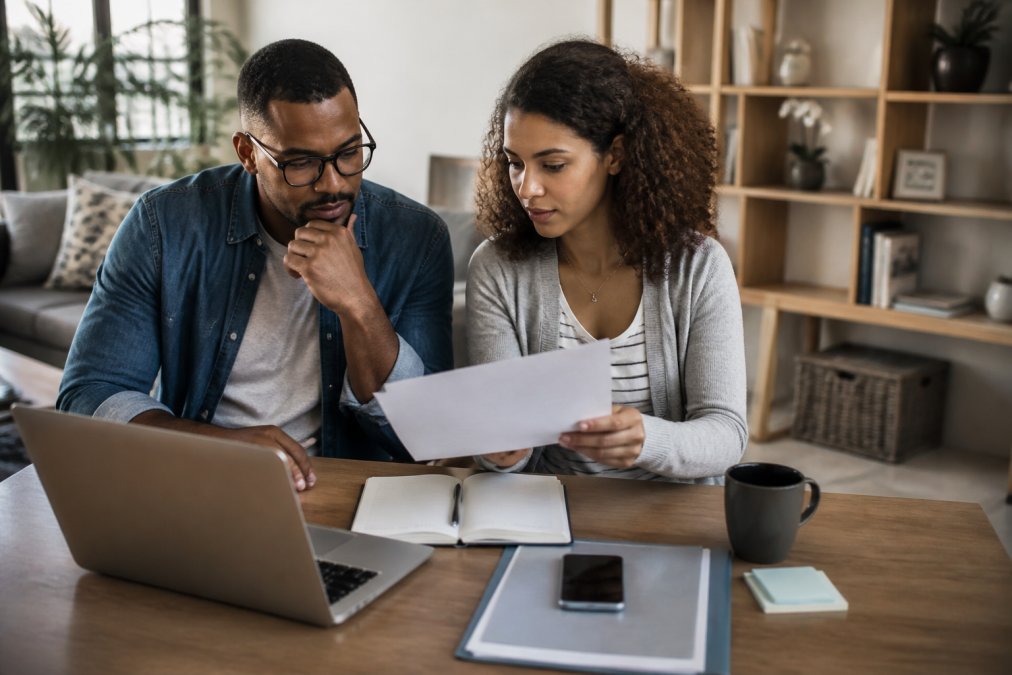 A couple reviewing a relationship consulting assessment report together on a laptop in a bright home office.