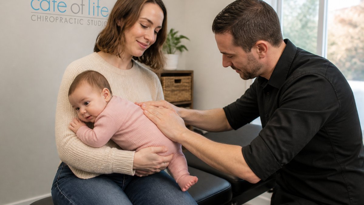 A parent holding a calm infant while a chiropractor gently assesses the baby's spine in a bright, welcoming clinic room with soft natural light