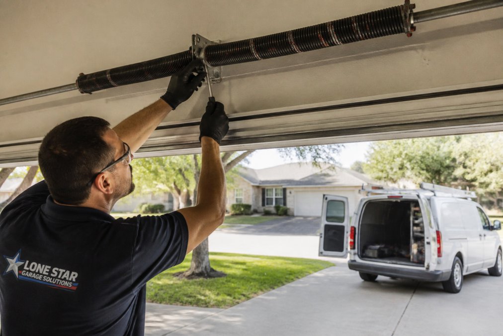 Technician inspecting a torsion spring assembly during a same day garage repair service