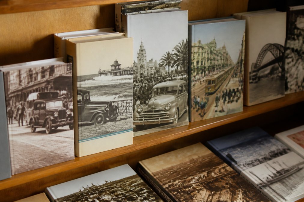 A collection of Australian nostalgia books displayed on a wooden shelf, showing book spines and covers from the 1950s era, with warm natural lighting highlighting the aged imagery and creating a nostalgic, inviting atmosphere