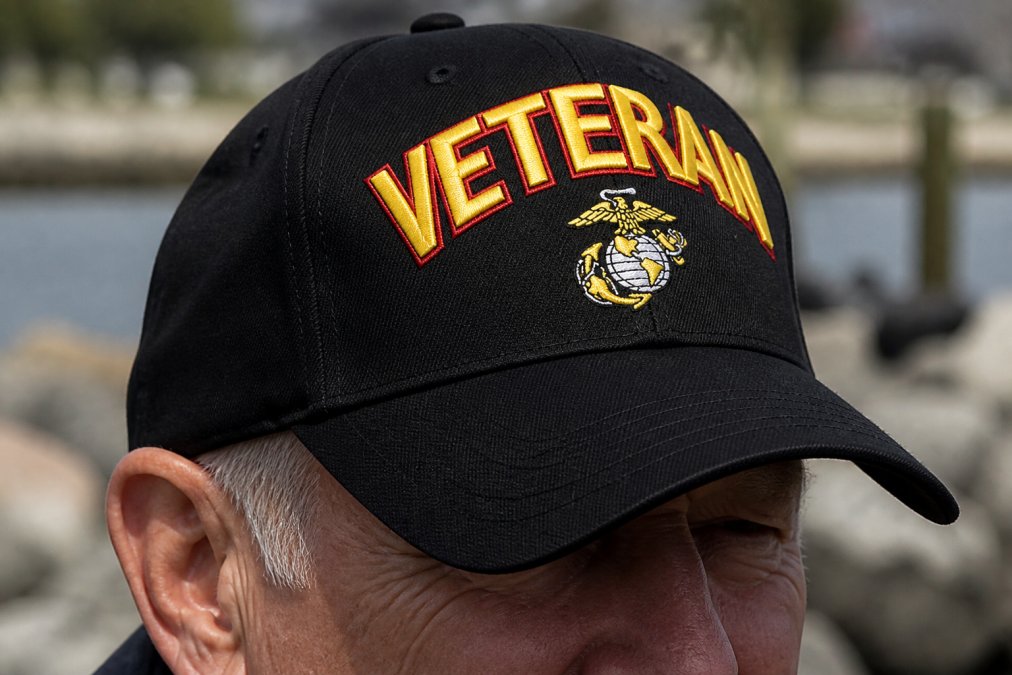 Close-up of military veteran wearing branch-specific embroidered cap with detailed insignia visible, showing embroidery quality and insignia placement with natural outdoor lighting