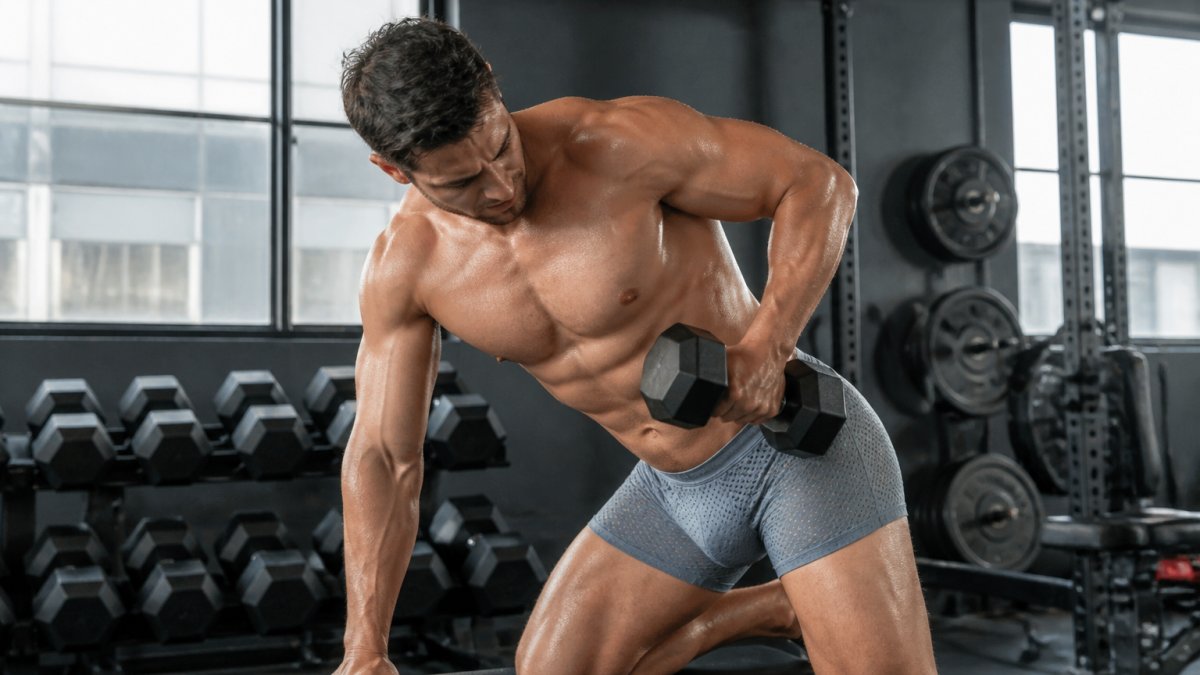 Athletic man in mesh boxer briefs demonstrating active movement during intense gym session, showing breathable fabric performance under physical exertion with visible sweat management