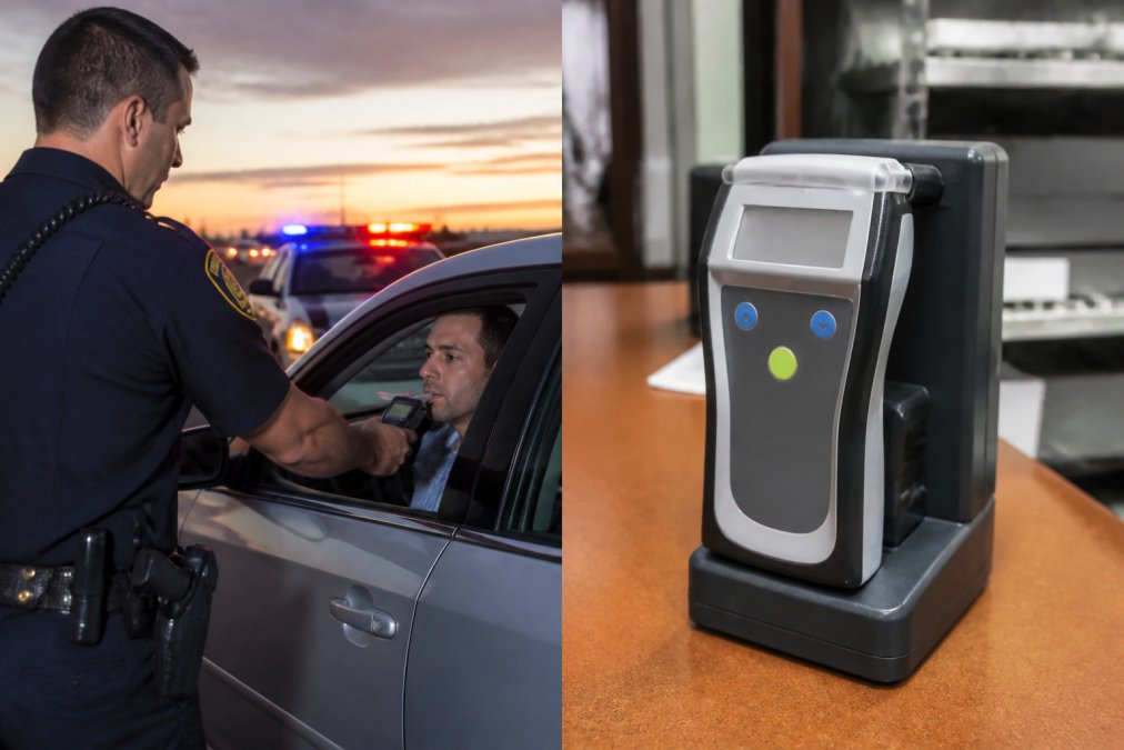 Police officer administering a preliminary alcohol screening test with a handheld breathalyzer device during a roadside traffic stop at dusk, with vehicle and emergency lights visible in background