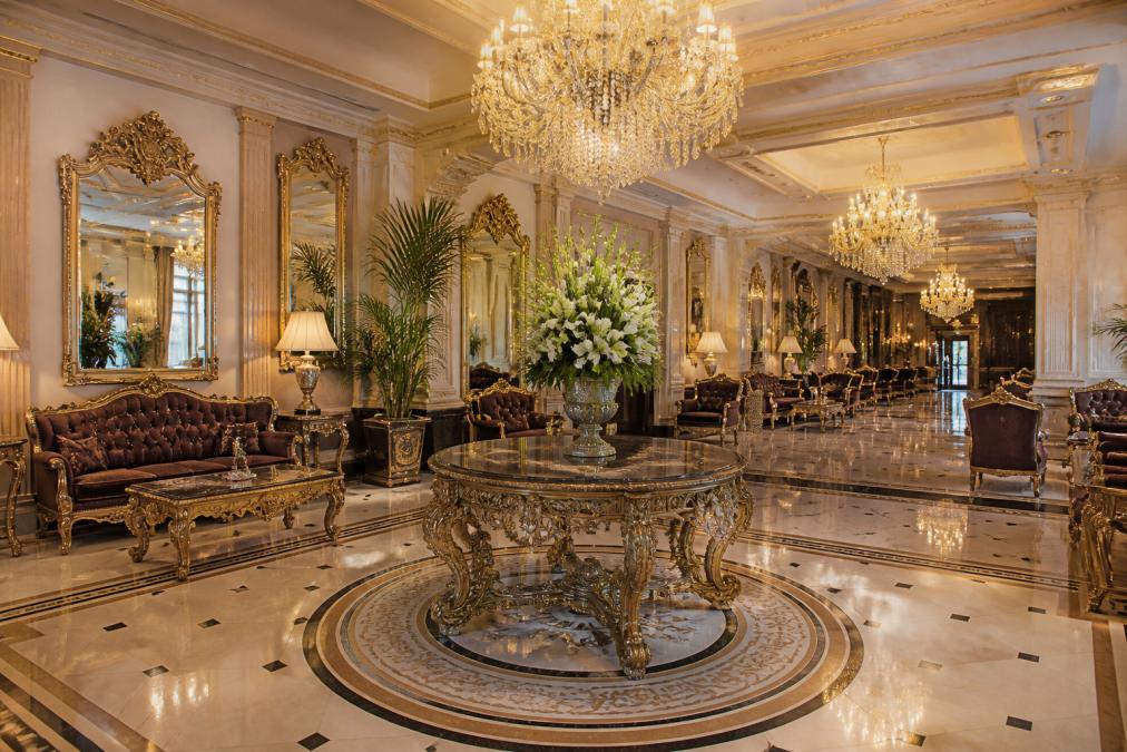 Elegante Hotellobby mit opulenten Barockmöbeln, vergoldeten Spiegeln, Marmorböden und Kristallleuchtern in warmem Licht, die luxuriöses Interieur Design und gepflegte Atmosphäre zeigt