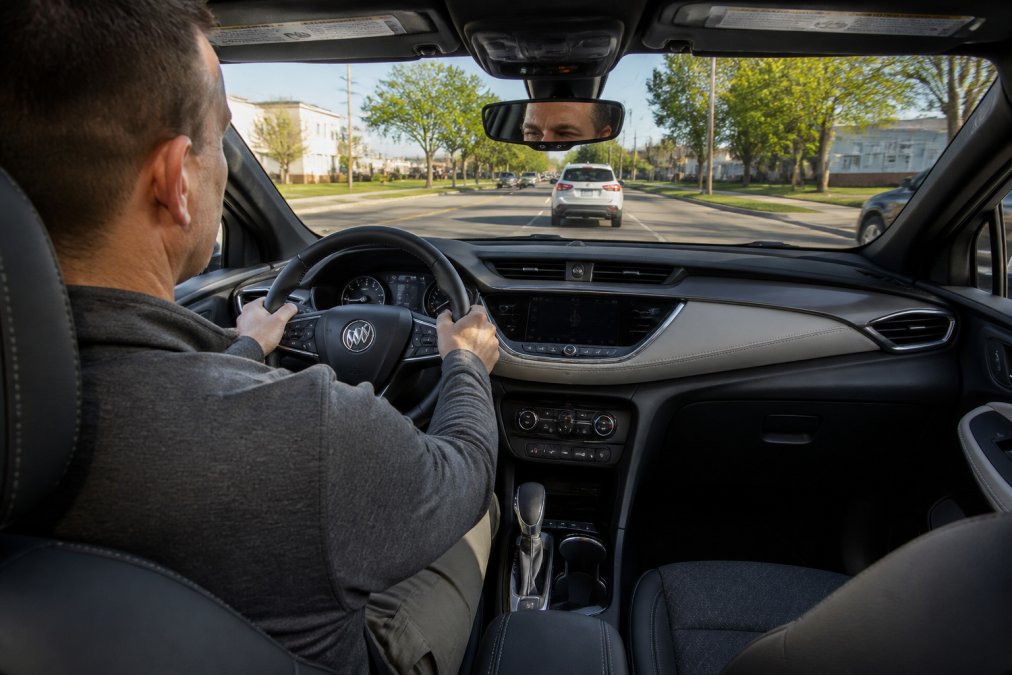 Interior cabin view of Buick Encore showing the steering wheel, dashboard, and comfortable seating during daytime driving on a commute route