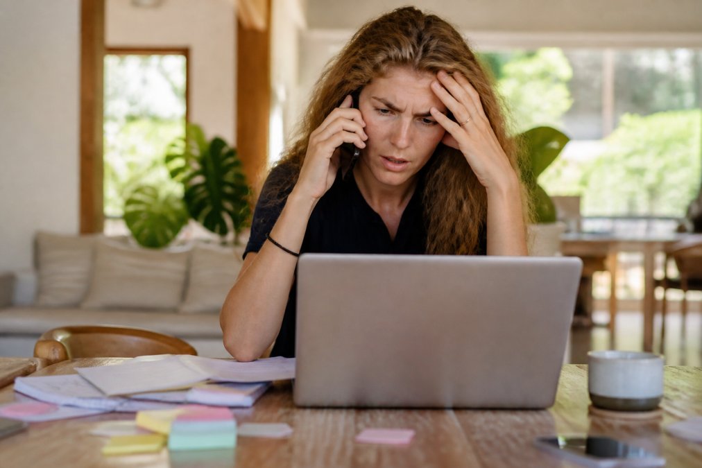 Founder at desk surrounded by multiple tasks, phones, notifications, and sticky notes, looking overwhelmed by competing demands, representing the founder bottleneck problem