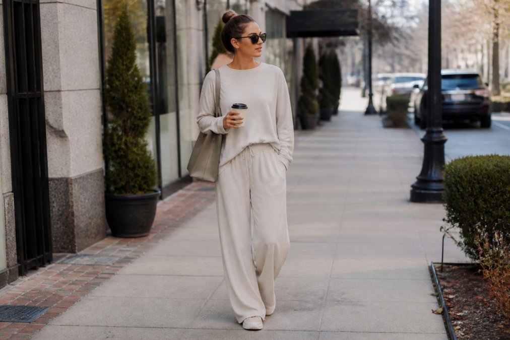 Woman in styled loungewear outfit with wide-leg pants and long-sleeve top, carrying a structured bag and ready for casual errands, photographed outdoors in natural daylight