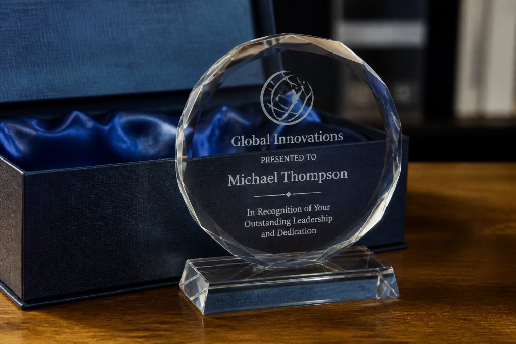 Close-up of a crystal award with company logo and employee name visible through fine laser engraving detail, professional lighting highlighting the personalization