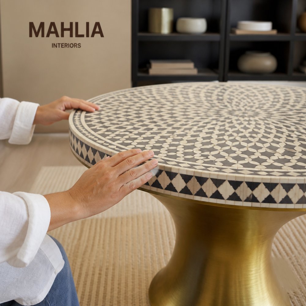 Close-up of hands examining the intricate bone pattern and brass base of handcrafted circular inlay tables