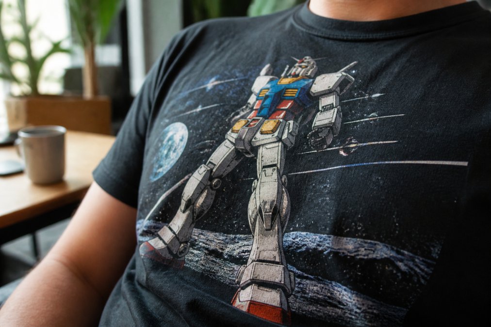 Close-up of a hand-screened graphic t-shirt displaying vibrant ink detail with rich color saturation and visible texture, worn by someone in casual indoor setting, highlighting the dimensional quality and durability of the print