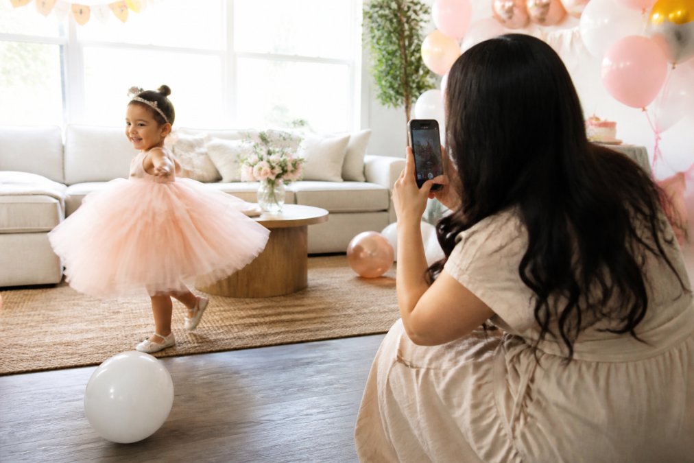 Toddler girl twirling in a tulle dress as part of stylish kids birthday outfits during a home photoshoot