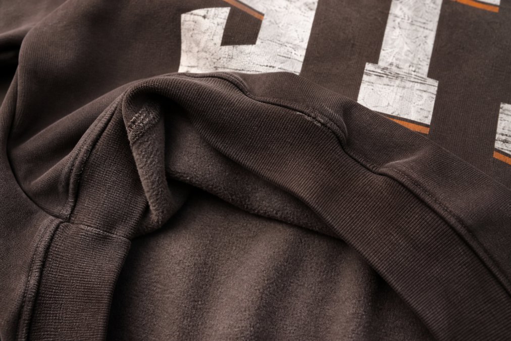 Close-up detail shot of premium heavyweight cotton fabric texture, showing brushed fleece interior and visible double-stitched seams with natural lighting highlighting the fabric weight and construction quality