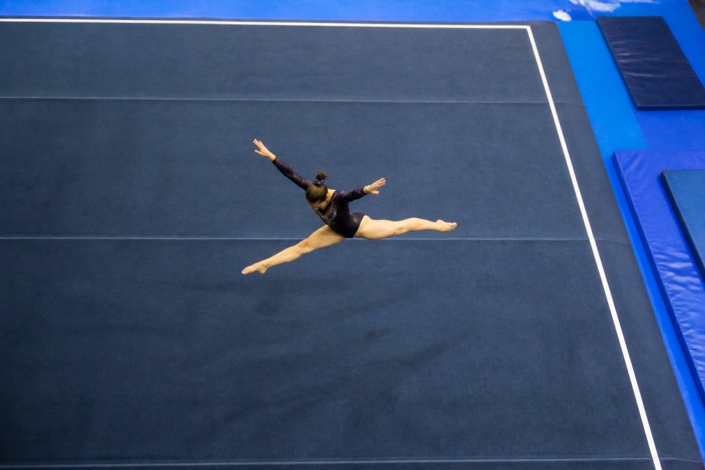 Overhead view of a competitive gymnast performing a skill on a professional spring floor in a well-lit training facility