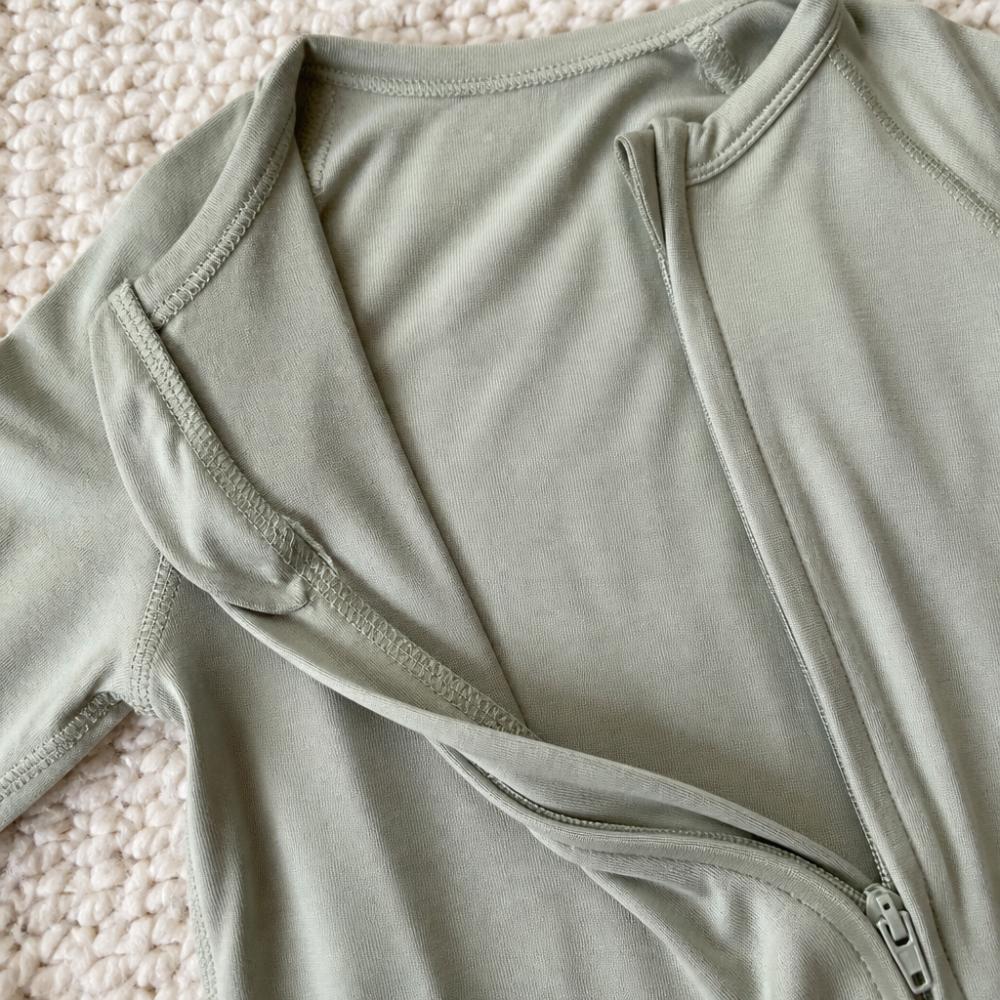 Close-up of soft bamboo fabric and internal seam construction on pajamas, showing tagless design and zipper detail with natural lighting