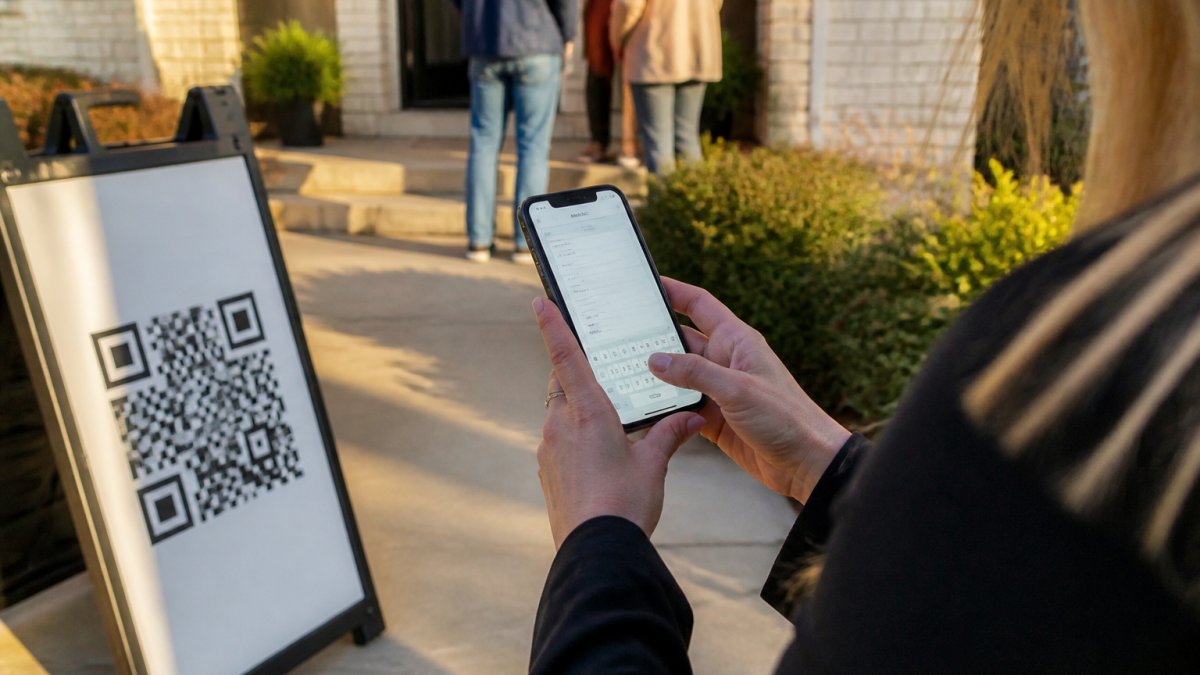 Real estate agent using open house software ROI to track visitor data via a QR code sign at an entrance