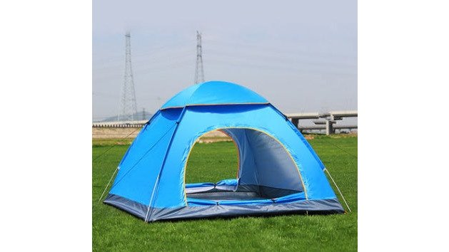 Two tents set up on a grassy campsite at golden hour, one a modern pop-up dome tent and the other a traditional freestanding tent, with a backpack leaning against a tree nearby