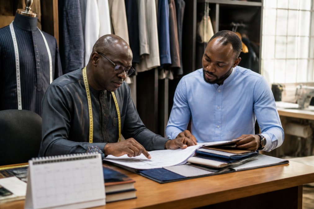 Checklist illustrating the bespoke clothing rush order process with a tailor and client reviewing fabric and timing.