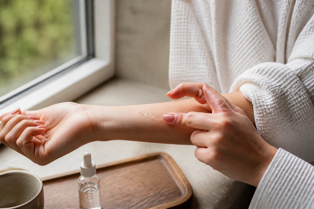Hands performing a careful patch test on the inner forearm with a small amount of copper peptide serum, showing proper application technique with natural window lighting