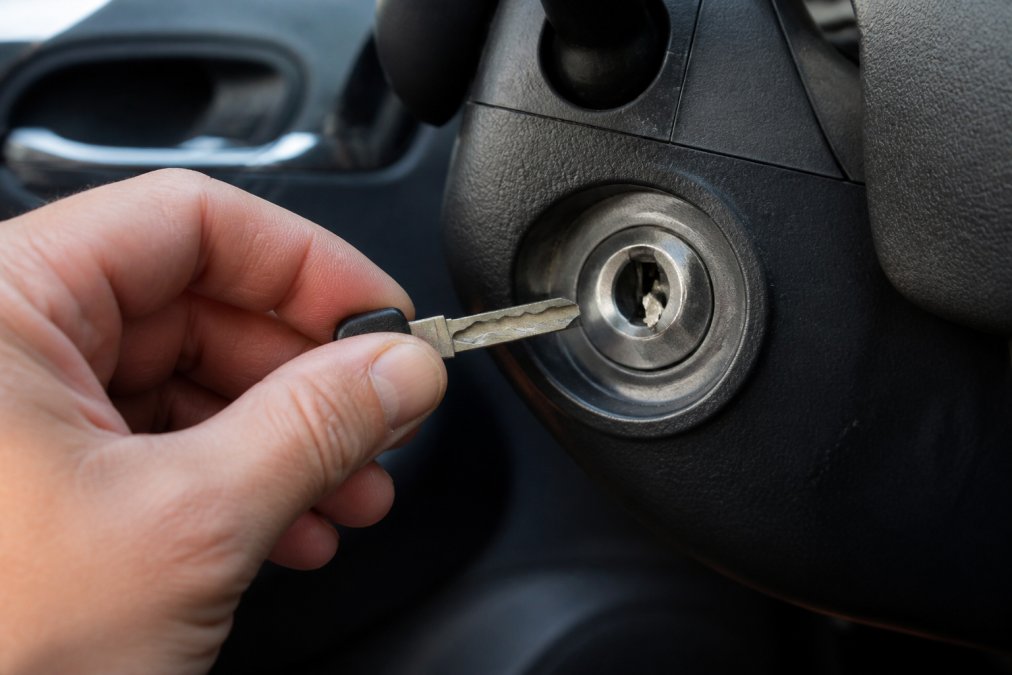 Driver holding a broken car key blade with the remaining fragment stuck inside the vehicle ignition switch