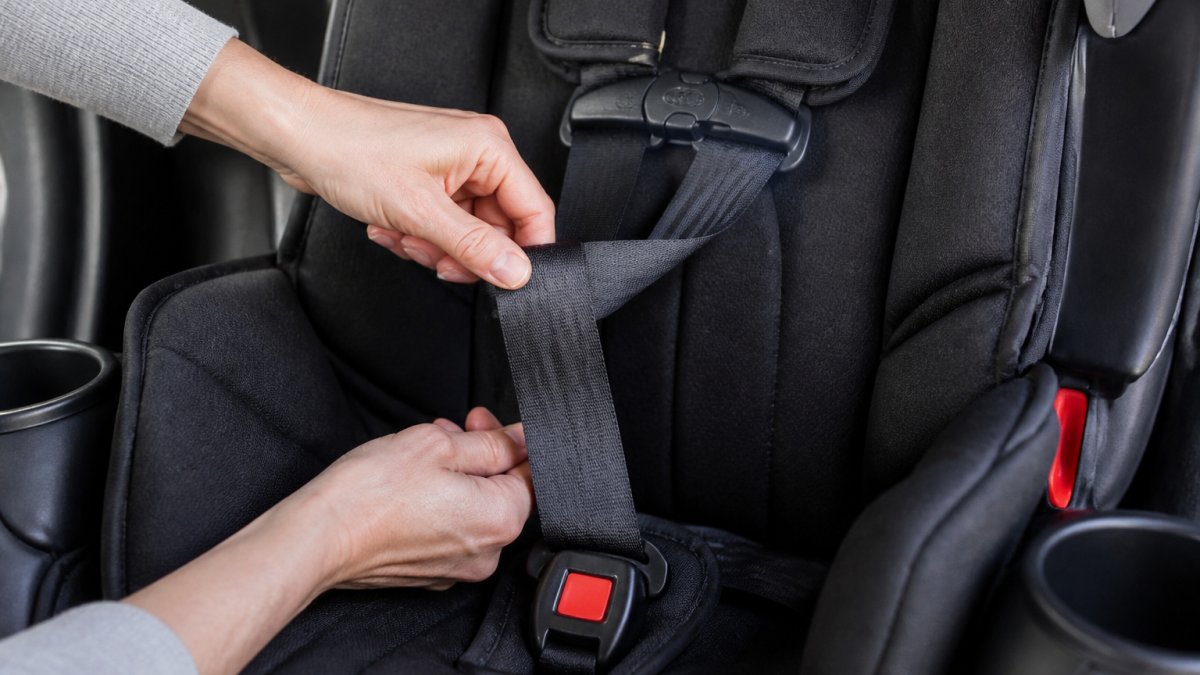 Step-by-step diagram showing hands untwisting and flattening a car seat harness strap to keep it aligned