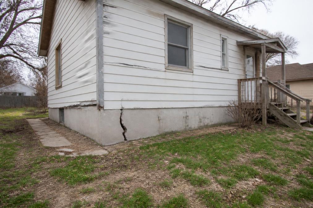 Exterior of Wichita home with visible foundation cracks and weathered siding, representing distressed properties that benefit from as-is cash sales
