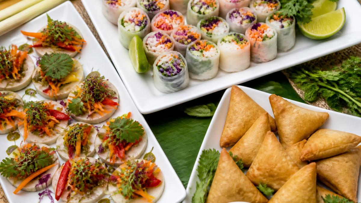 Vibrant gluten-free vegan catering spread with rice paper rolls, vegetable canapés, and golden samosas.