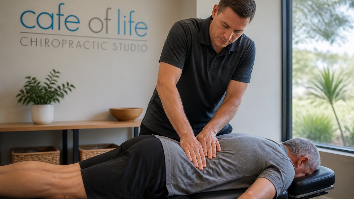 A chiropractor in a bright, welcoming clinic gently assessing a middle-aged patient lying face-down on a treatment table, hands placed along the lower back, calm and professional atmosphere