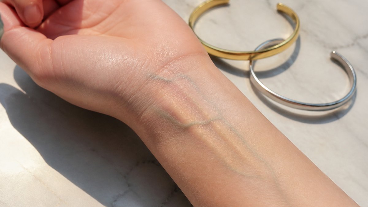 Woman's wrist in natural sunlight showing blue and green veins, with gold and silver bracelets nearby for comparison