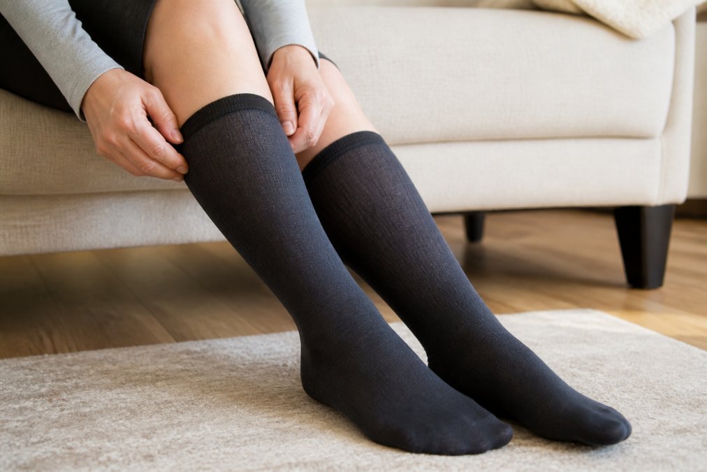Close-up of a person's foot and lower leg wearing well-fitting compression socks, showing the sock sitting comfortably on the calf without leaving marks or indentations on the skin, with natural lighting highlighting the proper fit