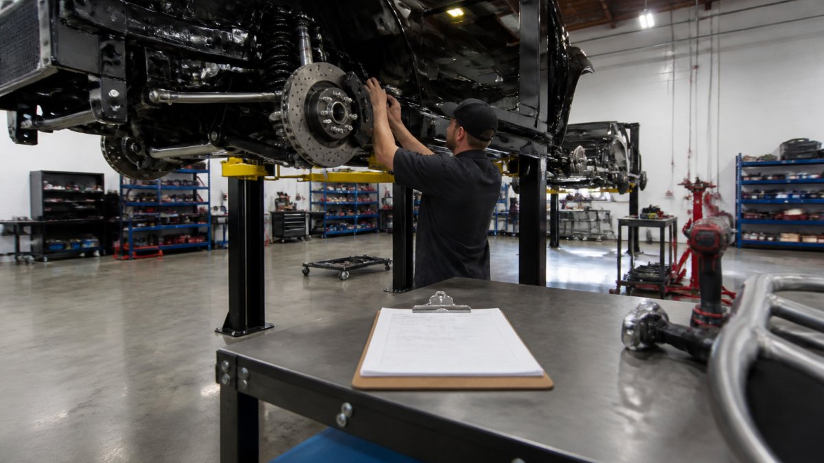 Technician inspecting a truck chassis suspension during custom builds in a professional workshop