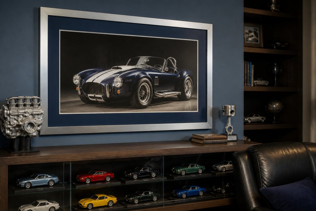 Modern man cave featuring a large framed automotive print with coordinating navy matting and brushed metal frame displayed above a vintage car model collection