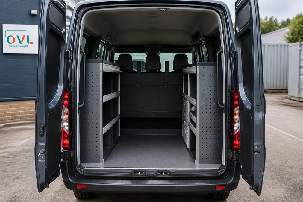 A UK crew van with its rear doors open, showing a shelving and drawer racking system fitted behind a bulkhead with a second row of seats in front, parked on a depot yard in daylight