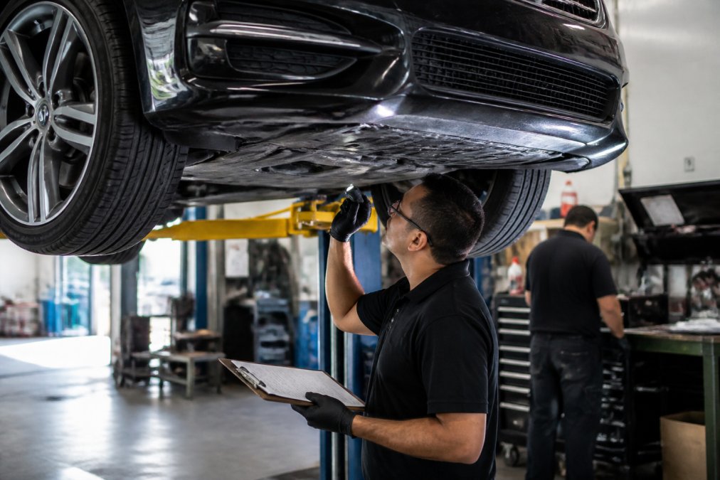 Mechanic inspecting a European sedan on a lift during professional foreign car service in a clean auto shop.