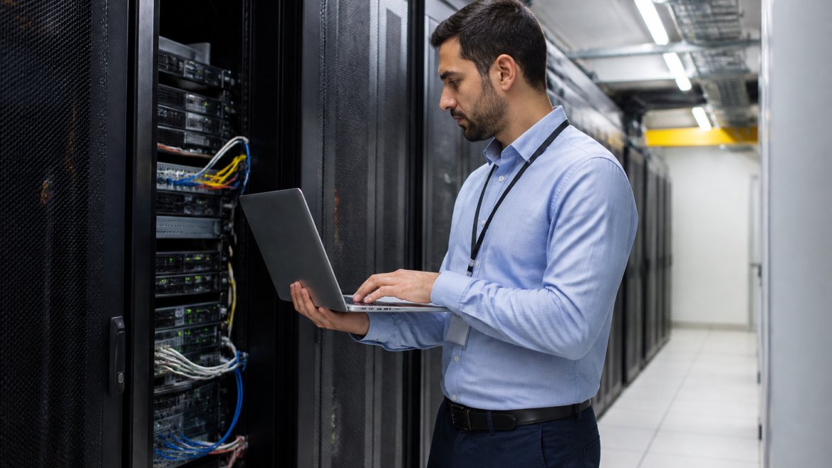 Security operations center with multiple monitors displaying live camera feeds, access logs, and system status indicators; security professional in professional attire reviewing real-time alerts at a modern workstation with multiple screens