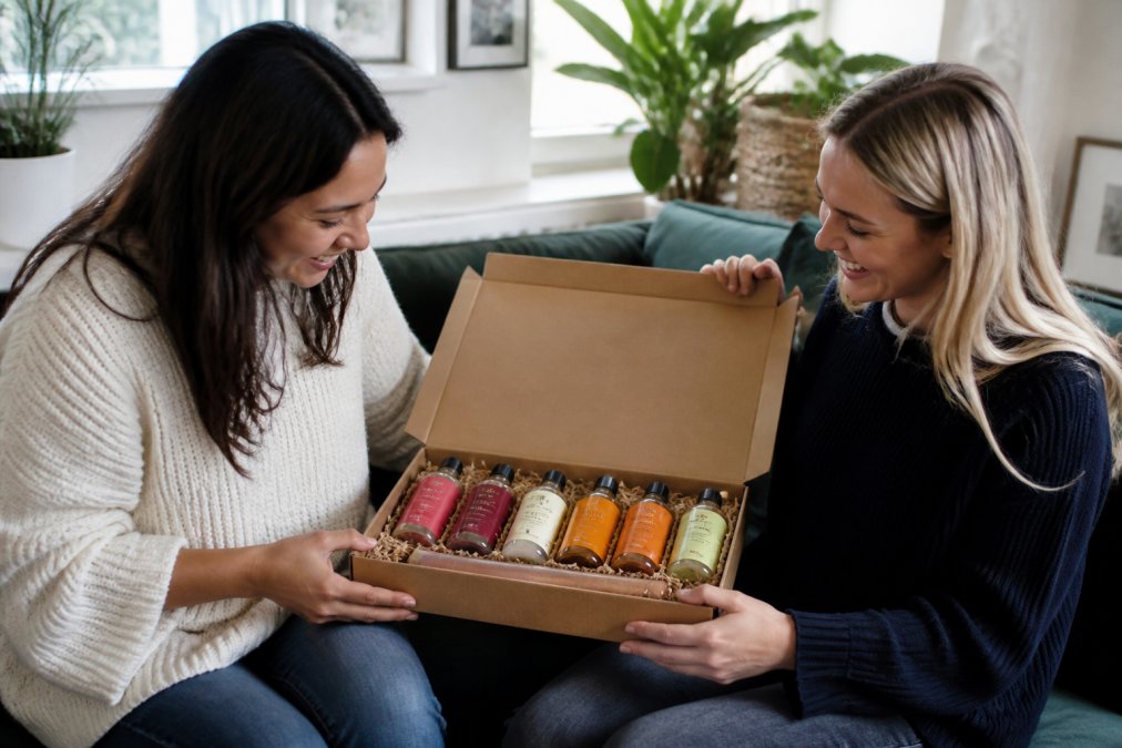 An elegant open cocktail gift box displaying premium bottled ready-to-drink cocktails with colourful labels and sophisticated branding, arranged neatly on a marble surface with soft natural lighting, ready for gifting