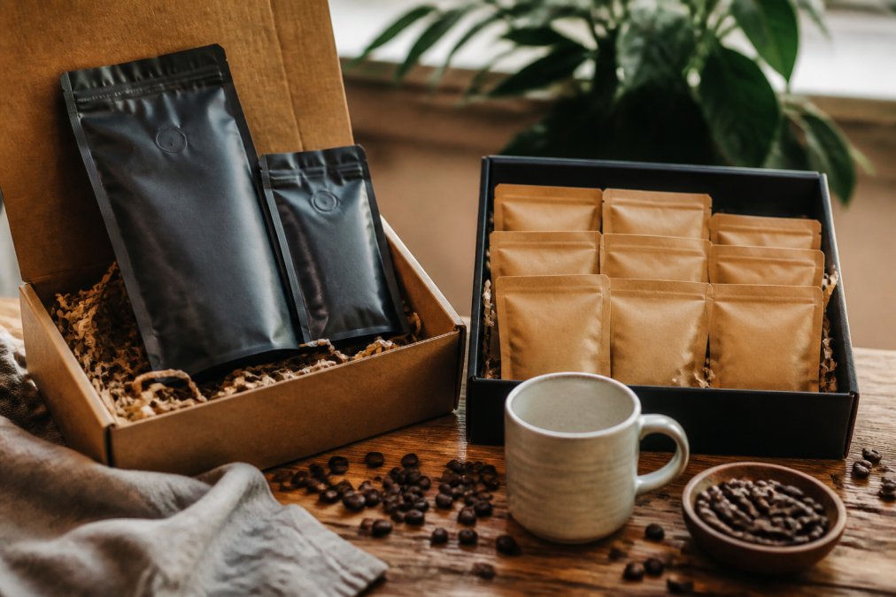 Comparison infographic displaying variety and contents of coffee gift sets arranged on a wooden table.