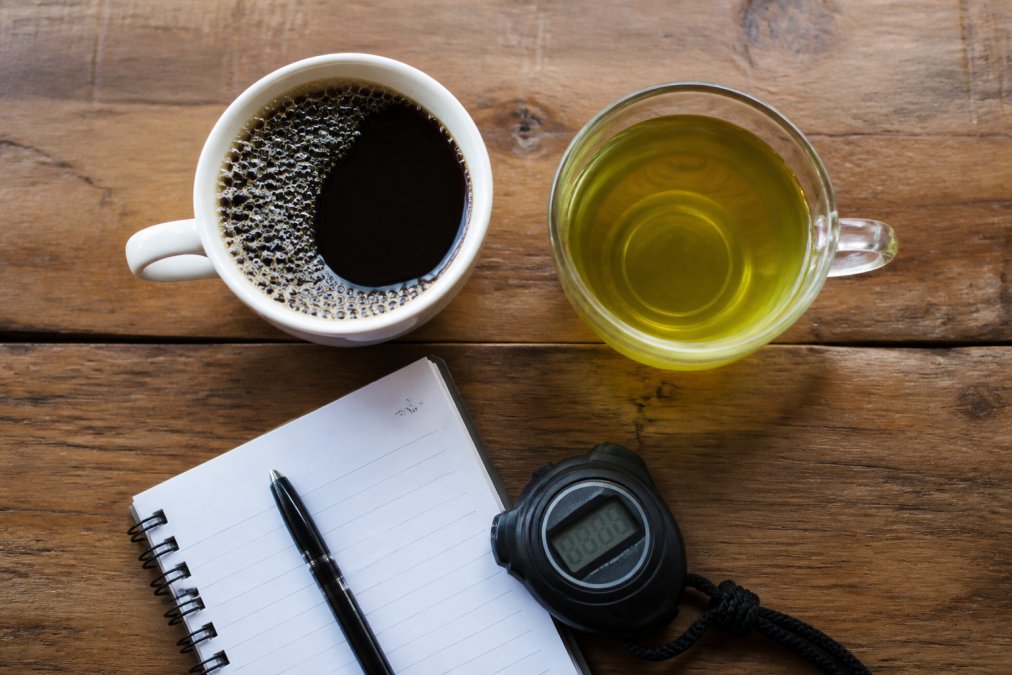 Diagram comparing coffee and green tea benefits for athletic energy levels on a notebook and stopwatch background