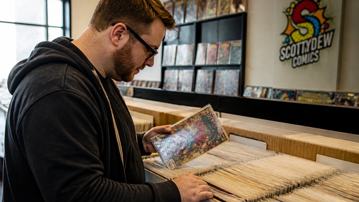 Collector browsing organized bargain bins while collecting comics on a budget at a local shop