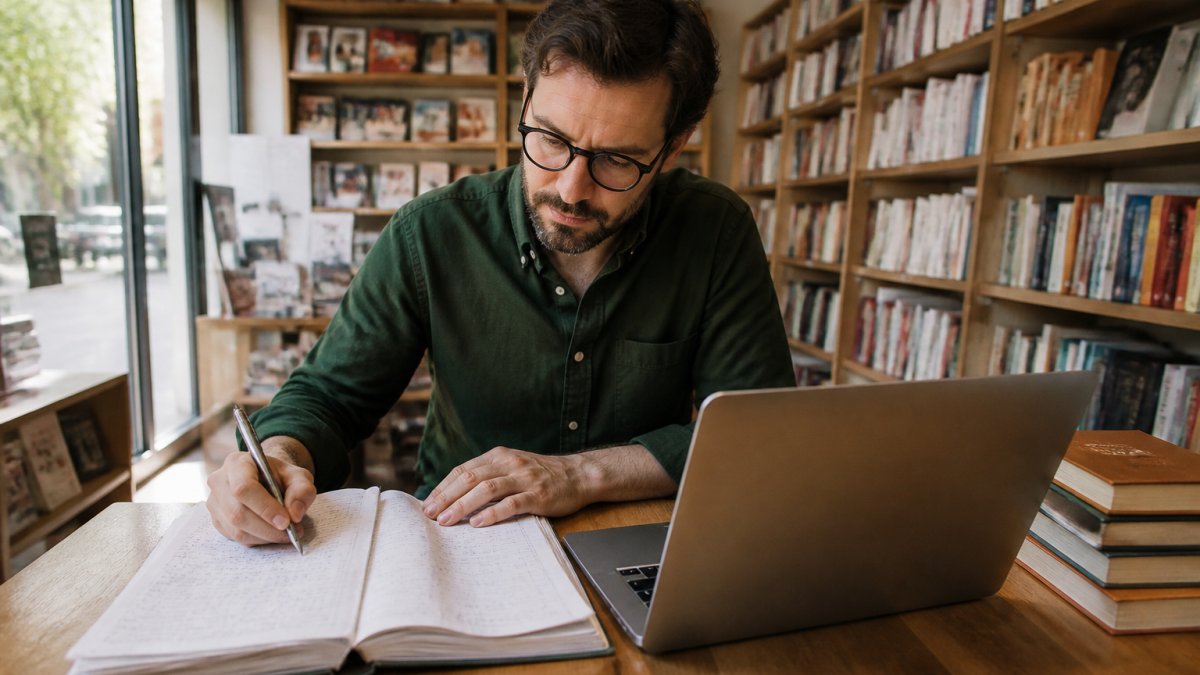 Libraio alla scrivania organizza le scadenze dei pagamenti fornitori in libreria tra registro e foglio di calcolo