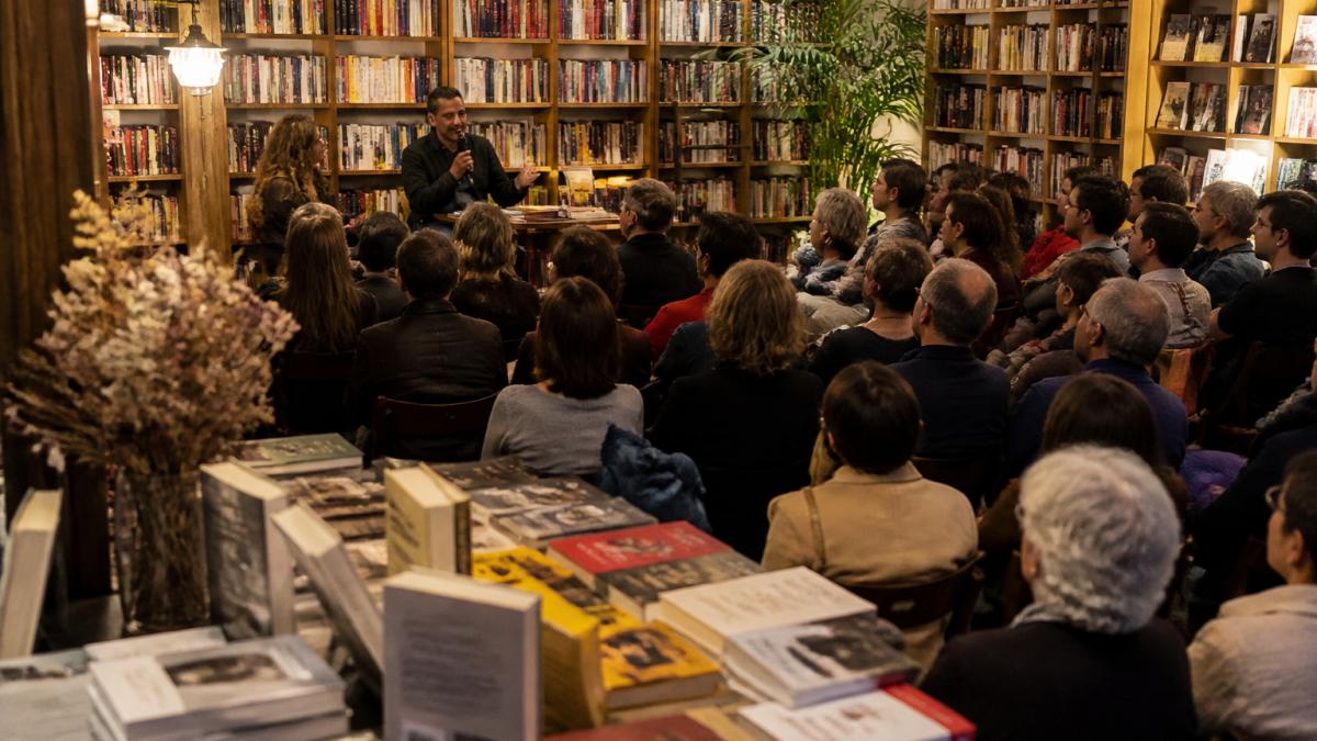 Pubblico attento ascolta l'autore durante uno degli eventi letterari in una libreria indipendente illuminata.
