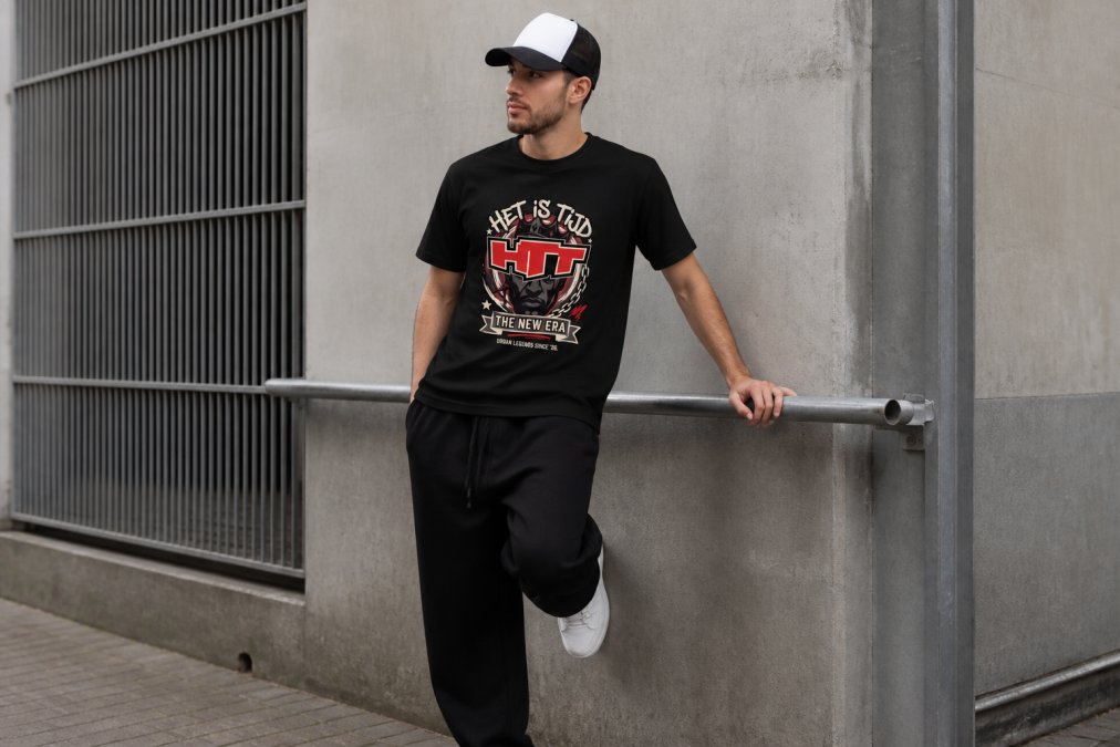 La modelo lleva una gorra trucker de diseño minimalista con un conjunto urbano informal compuesto por una camiseta extragrande y pantalones deportivos, de pie en un entorno urbano con iluminación natural