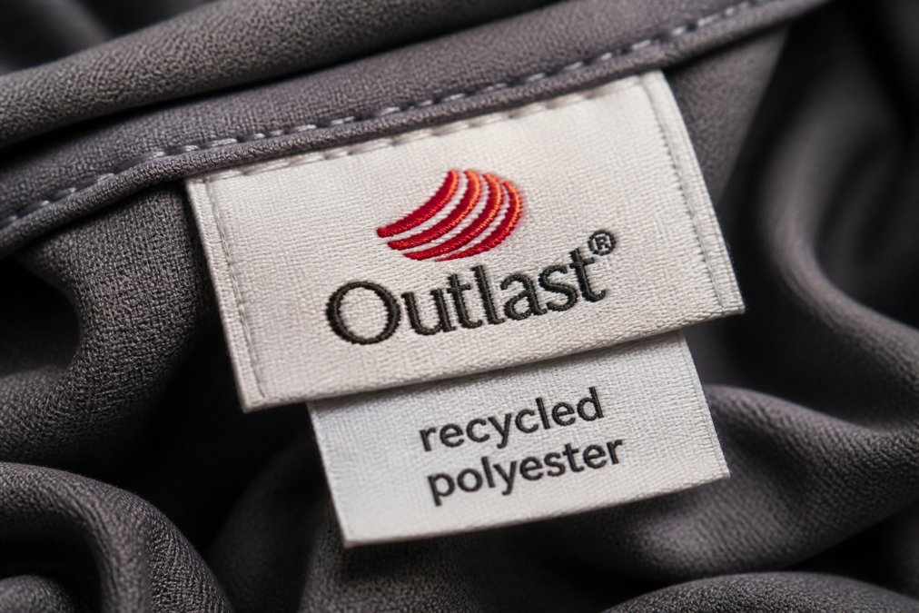 A macro shot of a fabric label showing 'Outlast' and 'recycled polyester' content tags