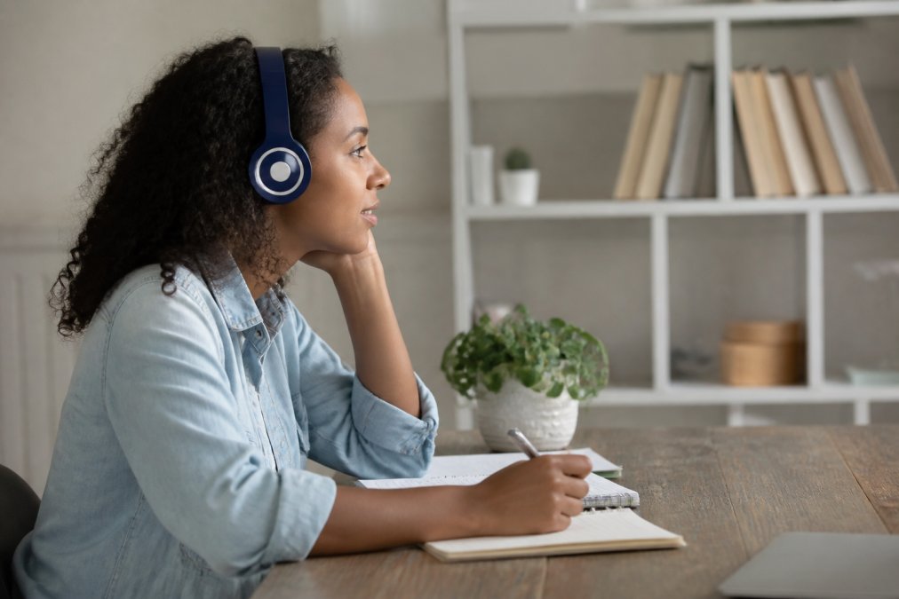Apprenant engagé regardant une vidéo pédagogique sur un écran avec sous-titres clairs visibles, environnement d'apprentissage lumineux et professionnel, notes prises à côté