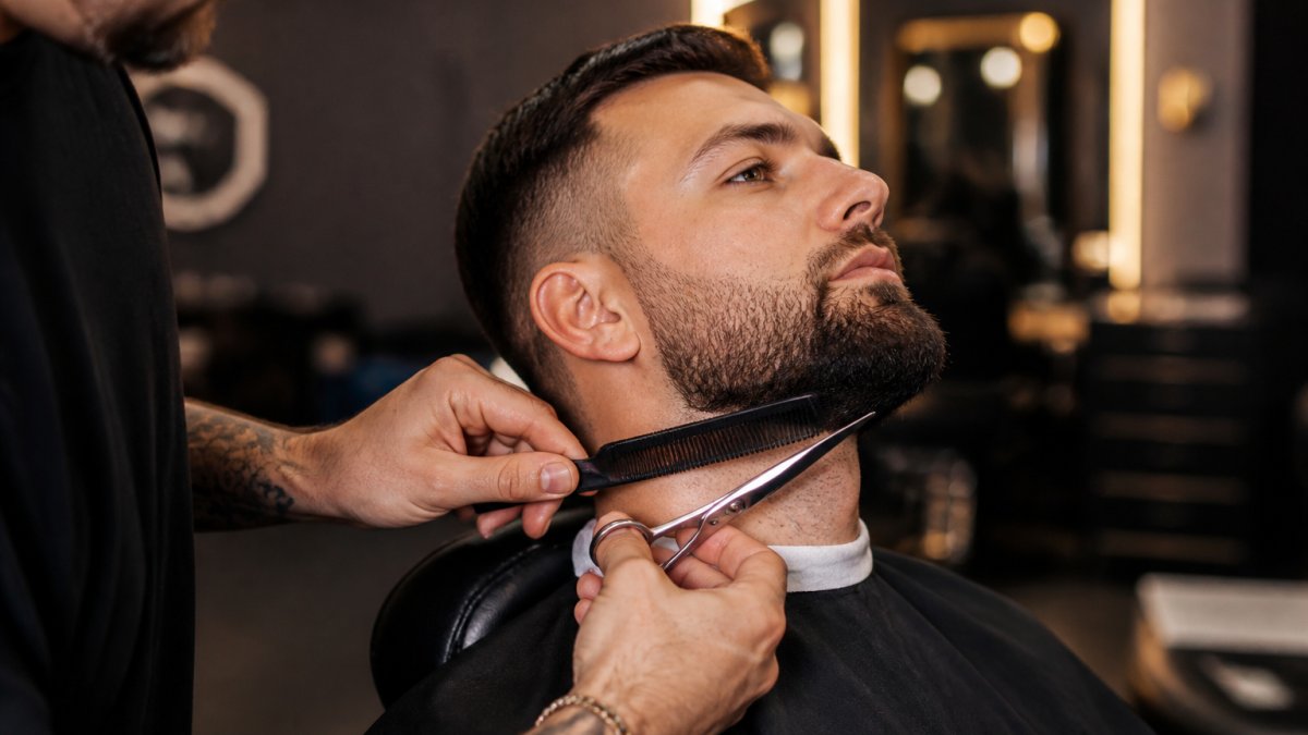 Un barbier taille la barbe d'un client pour un entretien d'embauche soigné dans un salon moderne.