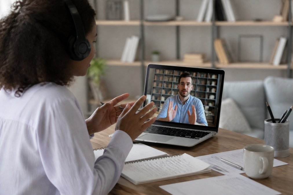 Formateur et apprenant collaborant à distance via écran vidéo, montrant l'interaction synchrone et l'engagement dans un environnement numérique d'apprentissage, avec documents et notes visibles sur le bureau
